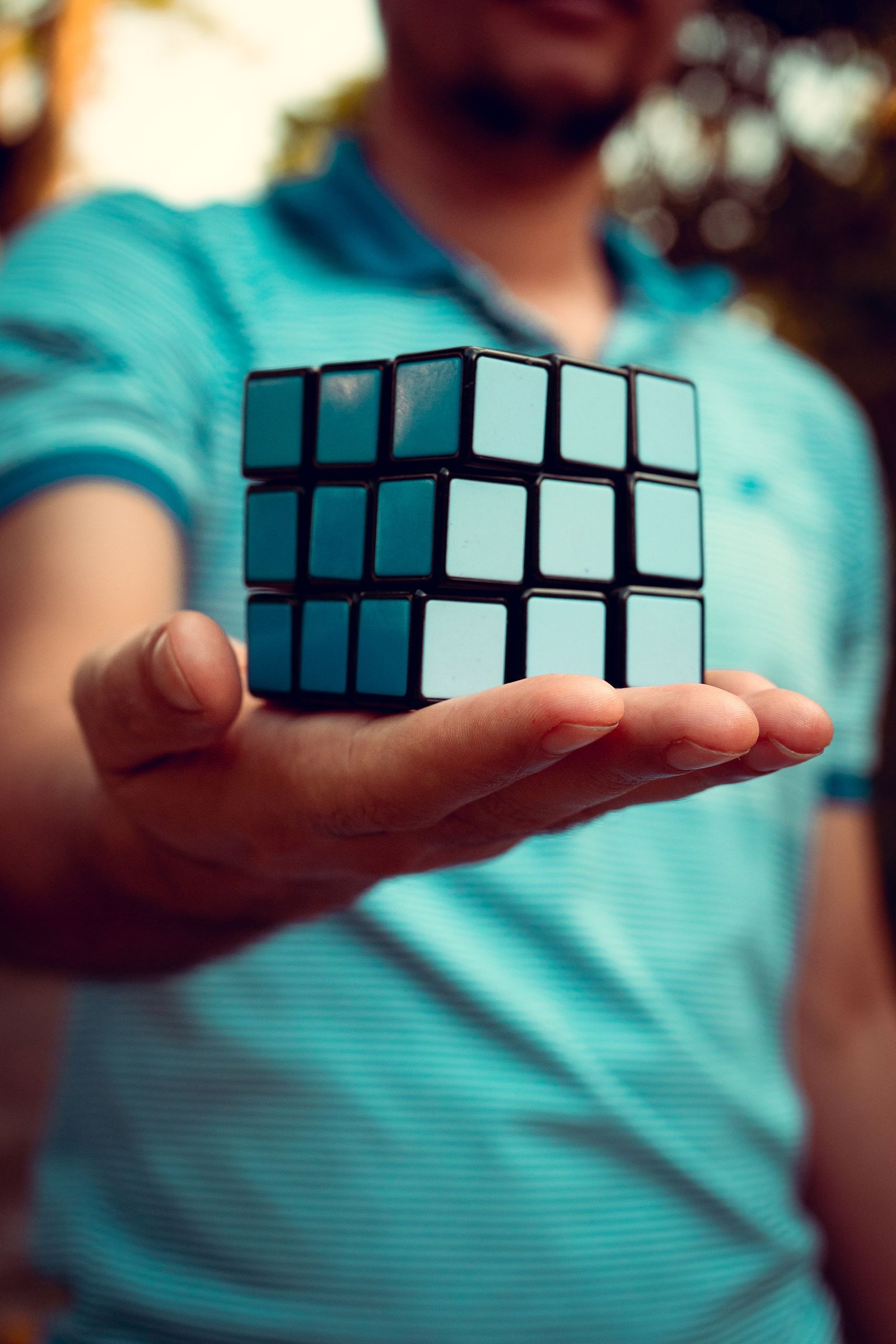 A close-up shot of a person holding a Rubik's Cube outdoors, displaying the cube prominently.